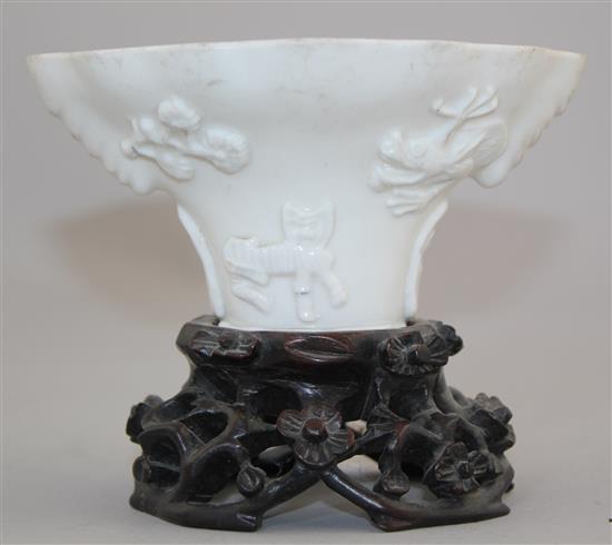 A Chinese Dehua blanc-de-chine libation cup, late 17th / early 18th century, 13cm, carved wood stand